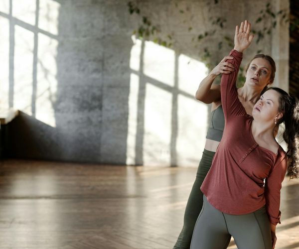 Woman stretching gracefully on a yoga mat in a sunlit room.